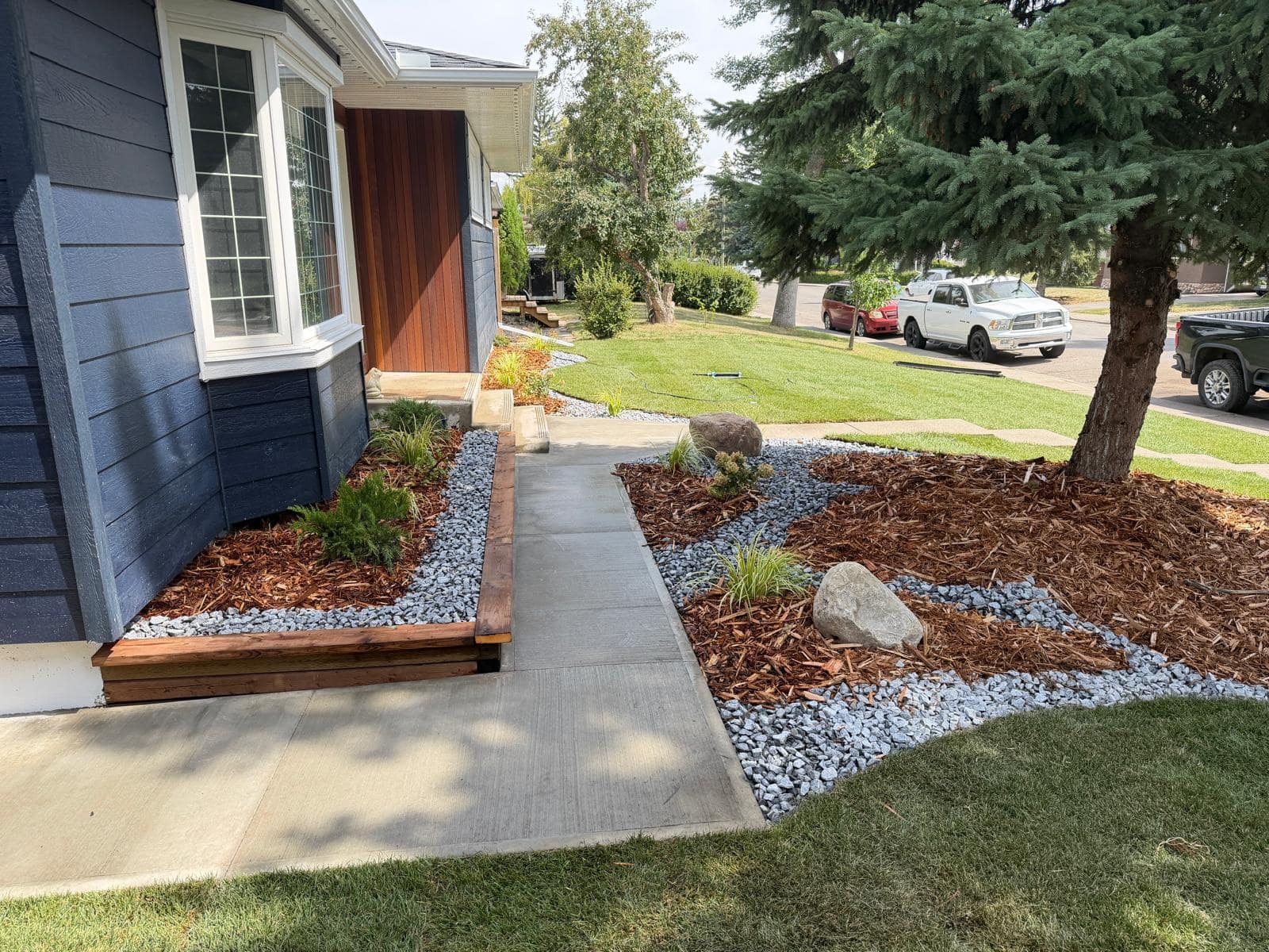 Detailed mulch and decorative rock beds flanking a new concrete walkway at a residential home