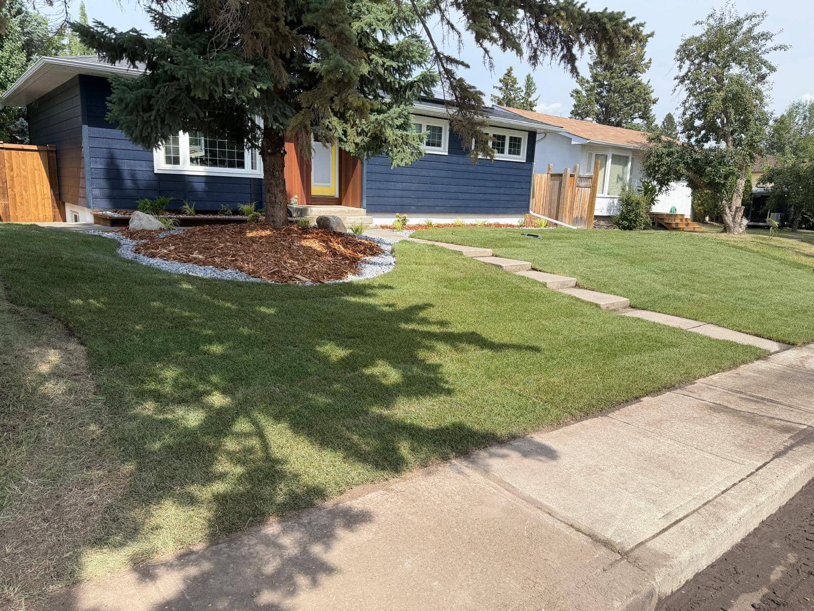 Completed front yard with fresh sod, mulch bed, rock edging and a stepping-stone path